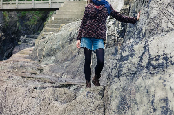 Mujer joven parada junto a las rocas en la costa — Foto de Stock