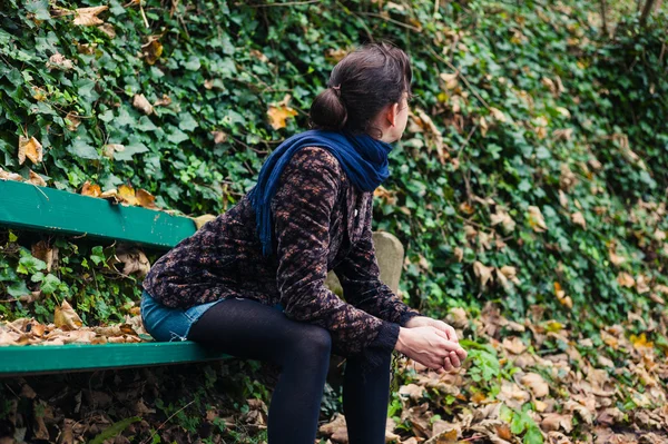 Mladá žena odpočívá na lavičce v lese — Stock fotografie