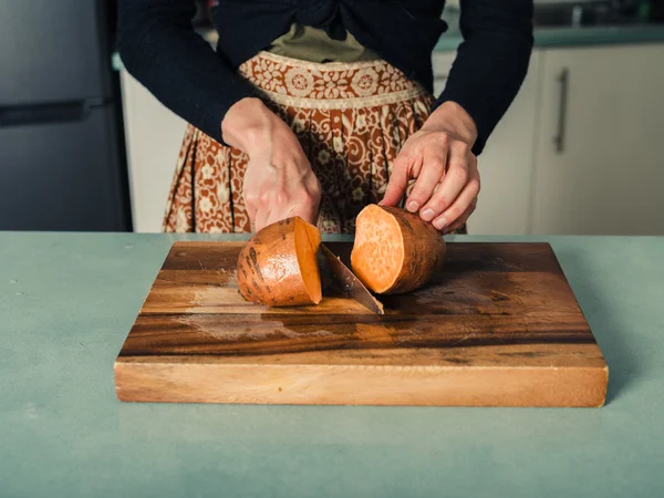Молодая женщина режет сладкий картофель — стоковое фото