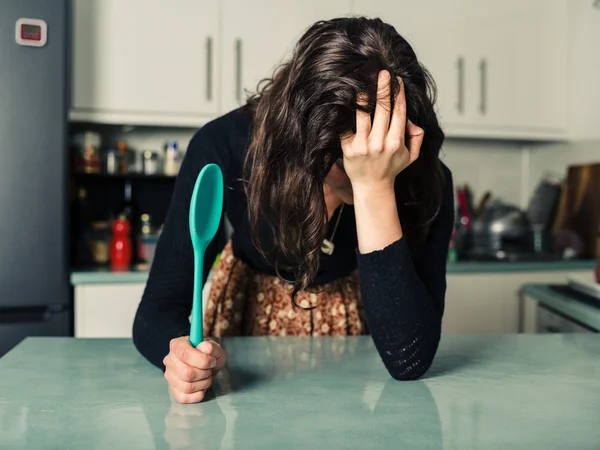 Mulher triste com colher na cozinha — Fotografia de Stock