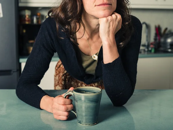 Jonge vrouw dagdromen met koffie in keuken — Stockfoto