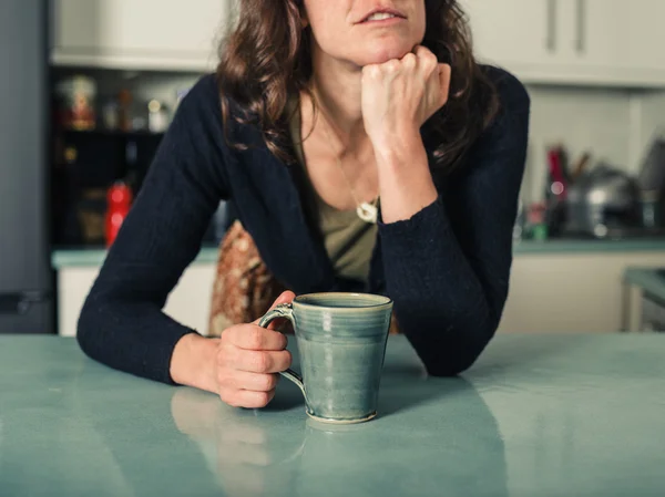 Mladá žena snění s kávou v kuchyni — Stock fotografie