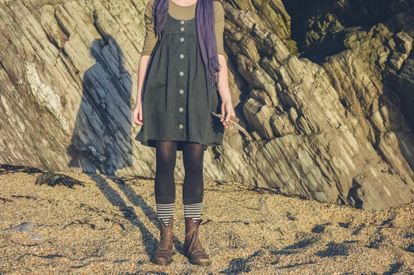 Jeune femme debout sur la plage avec du bois flotté — Photo