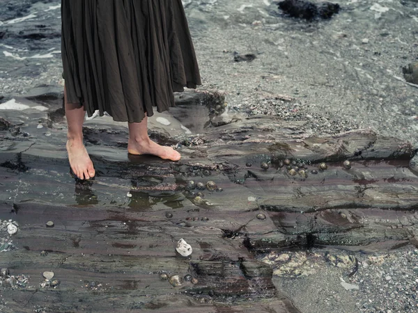 Voeten van jonge vrouw lopen op rotsen in het water — Stockfoto