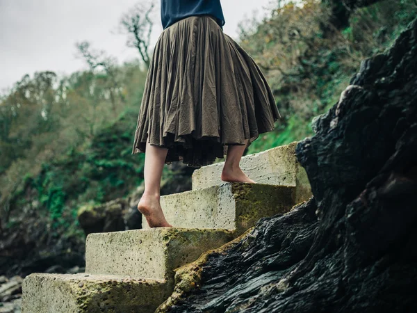 Barefoot woman walking up steps in nature — Stock Photo, Image