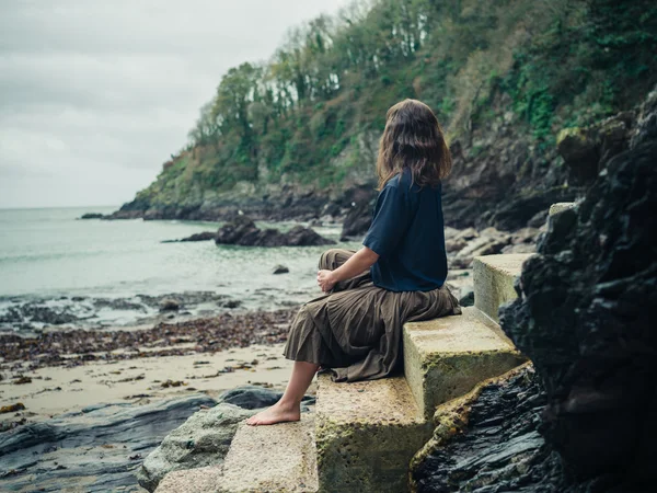Junge Frau entspannt sich auf Treppen in der Natur am Meer — Stockfoto