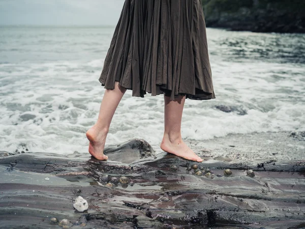 Pies de mujer joven caminando sobre rocas en el agua —  Fotos de Stock