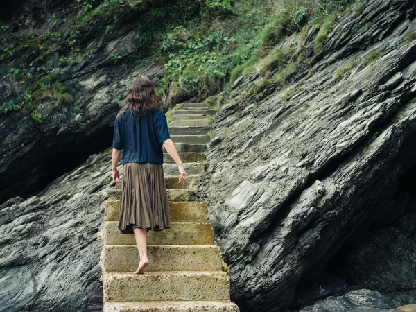 Nuori nainen kävelee ylös portaita kalliolla — kuvapankkivalokuva