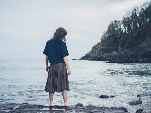 Giovane donna in piedi vicino all'acqua sulla spiaggia — Foto Stock