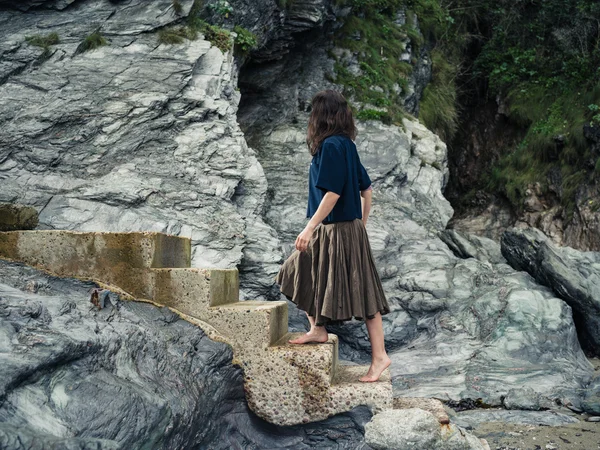 Young woman walking up steps by cliff — Stock Photo, Image