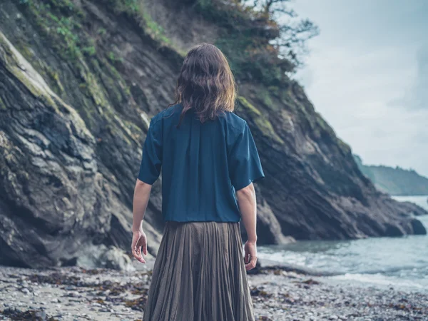 Giovane donna in piedi vicino alla scogliera sulla spiaggia — Foto Stock