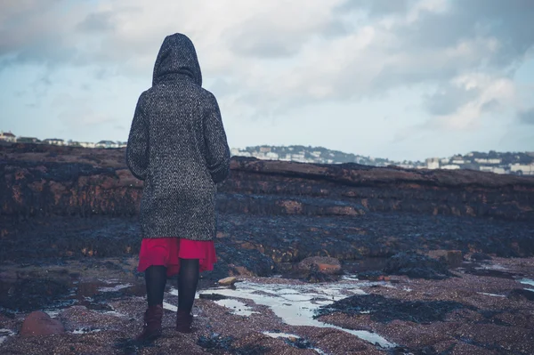 Ung kvinna i hooded coat promenader på stranden — Stockfoto