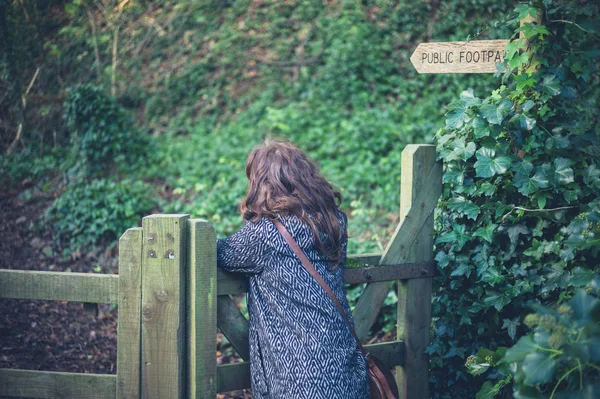 Woman leaning on fence in forest — Stock Photo, Image