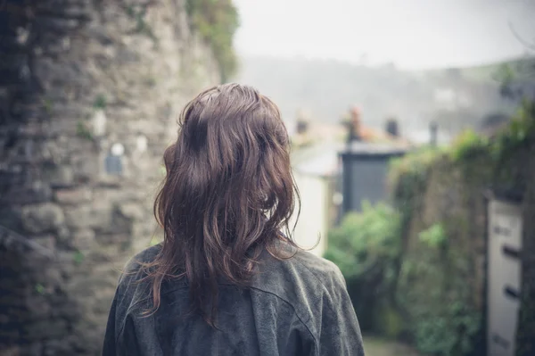 Vista trasera de una mujer joven caminando en un pequeño pueblo —  Fotos de Stock