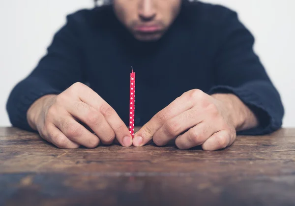 Sad young man with small candle — Stock Photo, Image