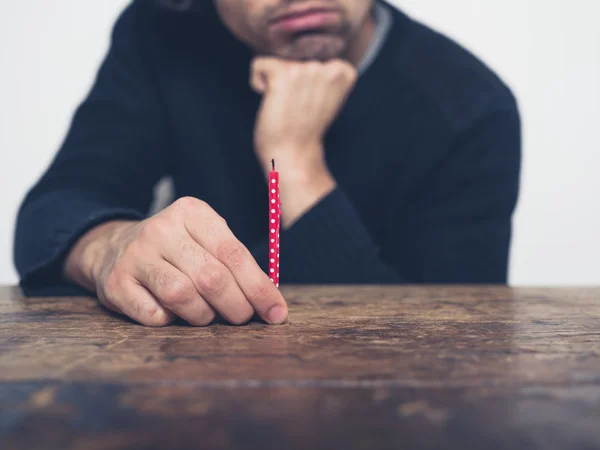 Sad young man with small candle — Stock Photo, Image