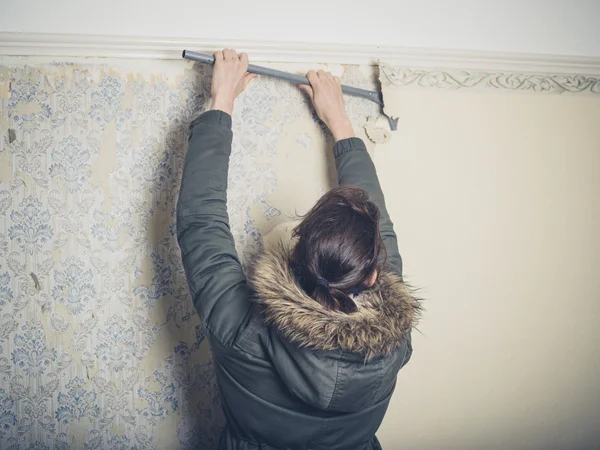 Young woman stripping wallpaper — Stock Photo, Image