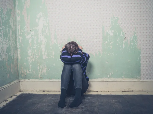 Traurige junge Frau sitzt auf dem Boden in leerem Raum — Stockfoto