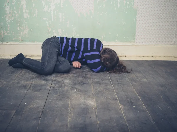 Sad young woman lying on floor — Stock Photo, Image