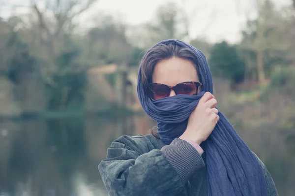 Mujer envolviendo su cara por el lago en el parque — Foto de Stock