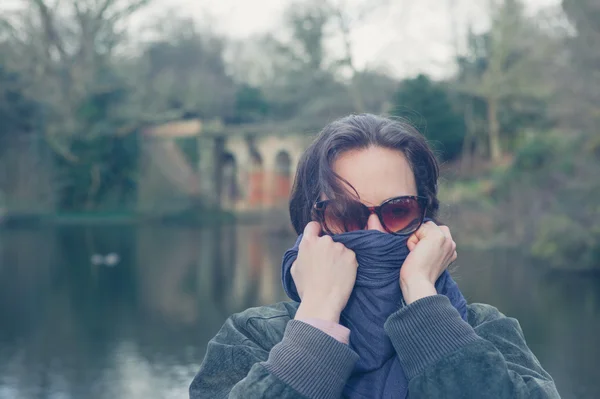 Vrouw verpakken omhoog haar gezicht door meer in park — Stockfoto