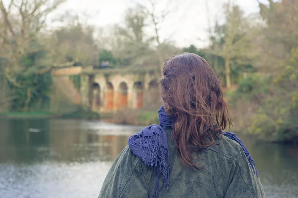 Jovem mulher por lago no parque — Fotografia de Stock