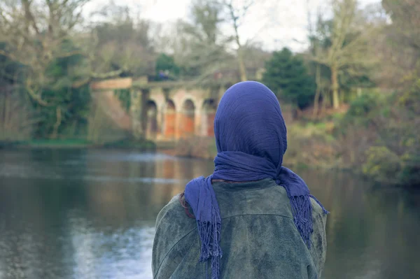 Jonge vrouw door meer in park — Stockfoto