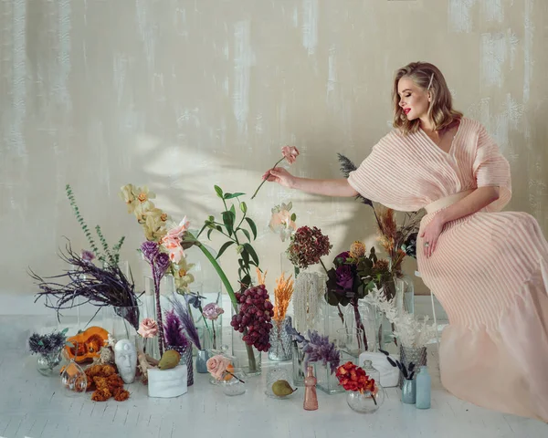 Elegant flicka sitter omgiven av blommor — Stockfoto