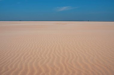 Beyaz kum tepeleri ve mavi gökyüzü olan minimalist bir manzara.