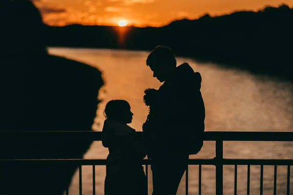 Padre con hija y perro en el fondo de los últimos rayos del sol — Foto de Stock