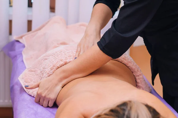 Masör 'ün elleri müşterinin vücuduna masaj yapıyor.