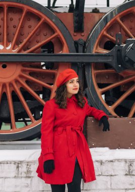 Trenin yanındaki tren istasyonunda bavullu kırmızı elbiseli kız. 