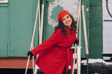 Trenin yanındaki tren istasyonunda bavullu kırmızı elbiseli kız. 