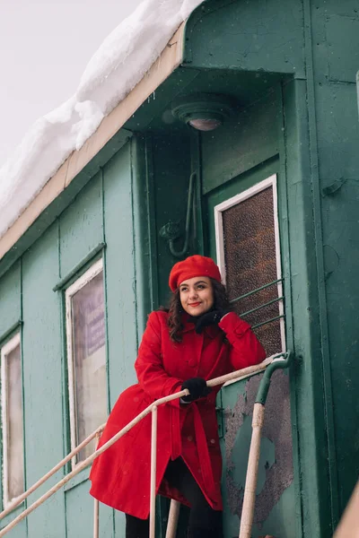 girl in red clothes with a suitcase at the train station near the train