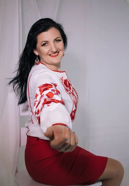 beautiful Ukrainian woman in an embroidered shirt on a light background