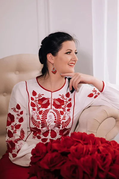 beautiful Ukrainian woman in an embroidered shirt on a light background