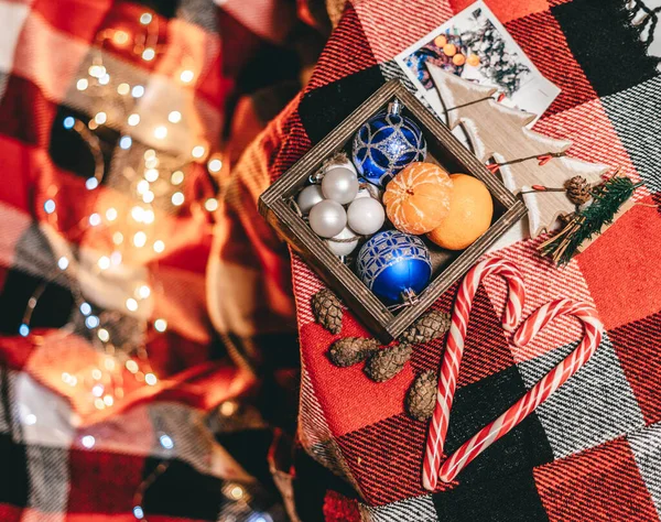 圣诞玩具在一个木制盒子里 盒子里放着棒棒糖和森林玩具 红色床罩上铺着人造雪和一棵木制小树 — 图库照片