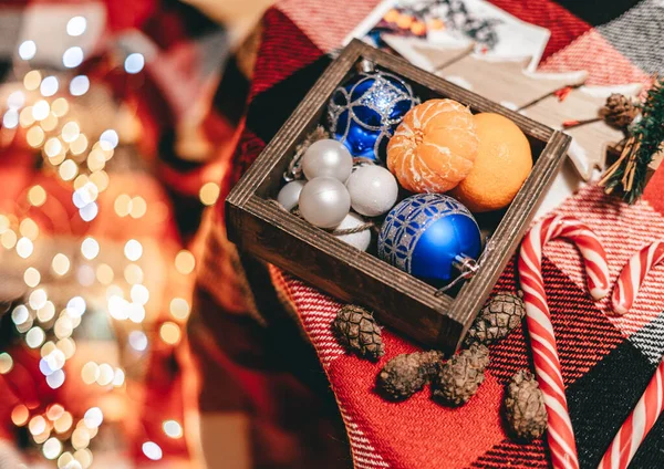 红色床罩上有柑橘和圣诞节蓝色玩具的木盒 — 图库照片