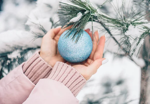 冬季森林中的女性手中拿着圆形蓝色圣诞树玩具 — 图库照片