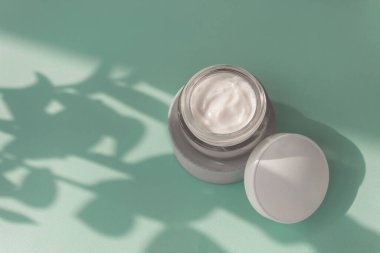 Yumuşak mavi arka planda cam kavanozda beyaz krema