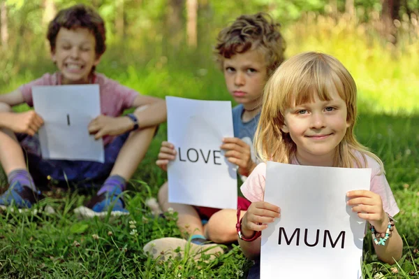 Tres niños con el signo Amo a mamá —  Fotos de Stock