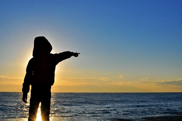 Silhouette di un ragazzo che indica il mare — Foto Stock