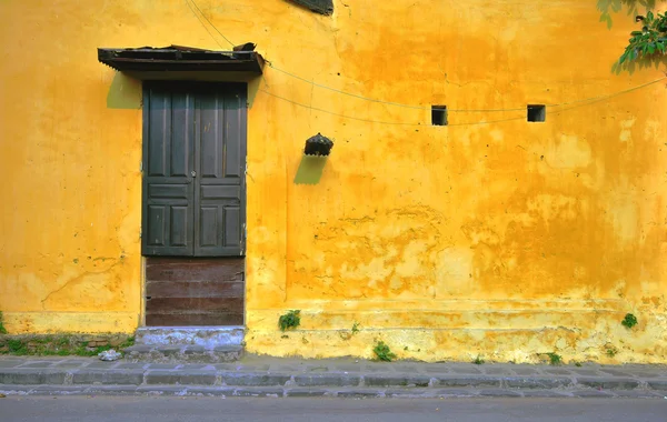 Yellow wall with a brown wooden door — Stock Photo, Image