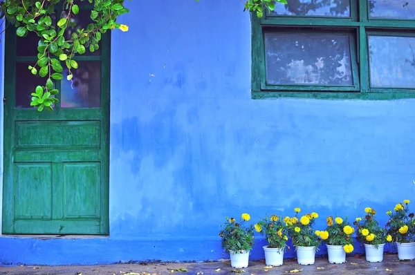 Antigua casa azul con flores amarillas en la entrada Fotos De Stock Sin Royalties Gratis