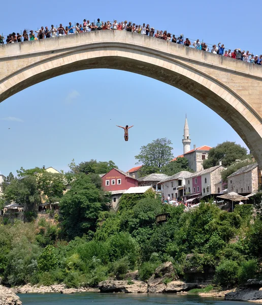 Hombre saltando desde el puente en el casco antiguo de Mostar — Foto de Stock
