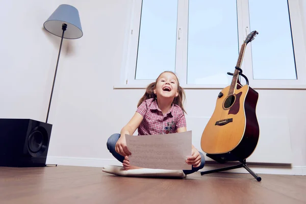 Mała dziewczynka uczy się grać na gitarze z nut. Szkoła muzyczna dla dzieci.Notacja muzyczna. Obrazek Stockowy