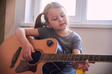 Küçük bir kız notalardan gitar çalmayı öğreniyor. Çocuklar için müzik okulu. Müzik notaları..
