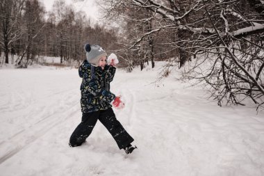 Kışın bir çocuk temiz havada kartopu oynar.