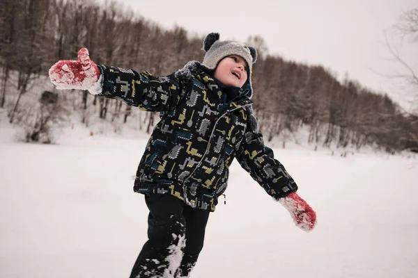 Ребенок зимой играет в снежки на свежем воздухе — стоковое фото