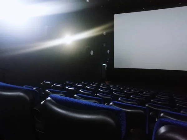 Uma sala de cinema vazia com assentos azuis. Tela branca para mostrar filmes. Lugar para o rótulo — Fotografia de Stock